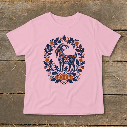 Light pink t-shirt featuring a folk art illustration of a goat surrounded by leaves and pumpkins.