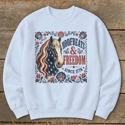 White sweatshirt featuring a horse with patriotic mane, "Hoofbeats & Freedom Since 1776" text.