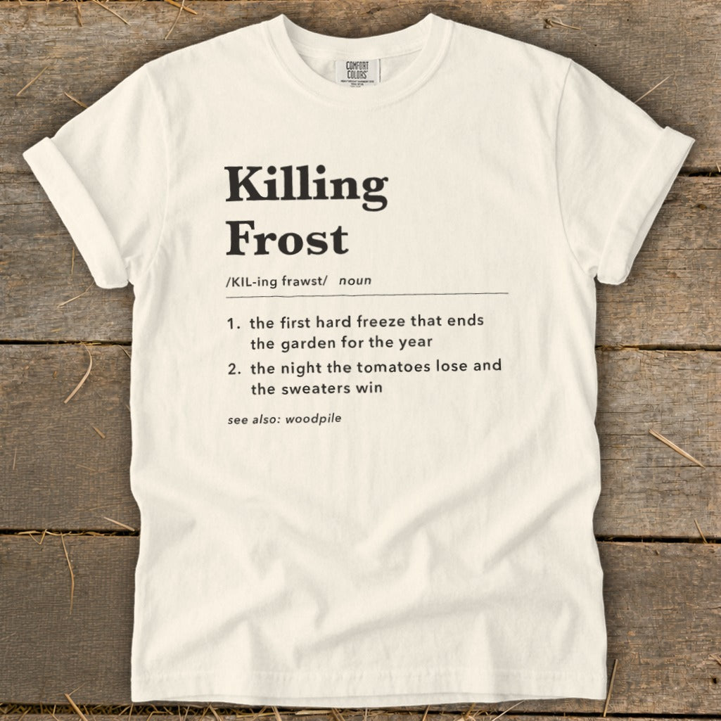 Off-white crewneck t-shirt featuring black dictionary-style text defining Killing Frost on a rustic wooden background.