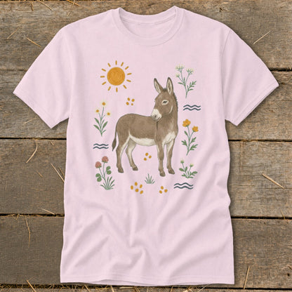 Light pink t-shirt with a watercolor illustration of a donkey surrounded by flowers and a sun.