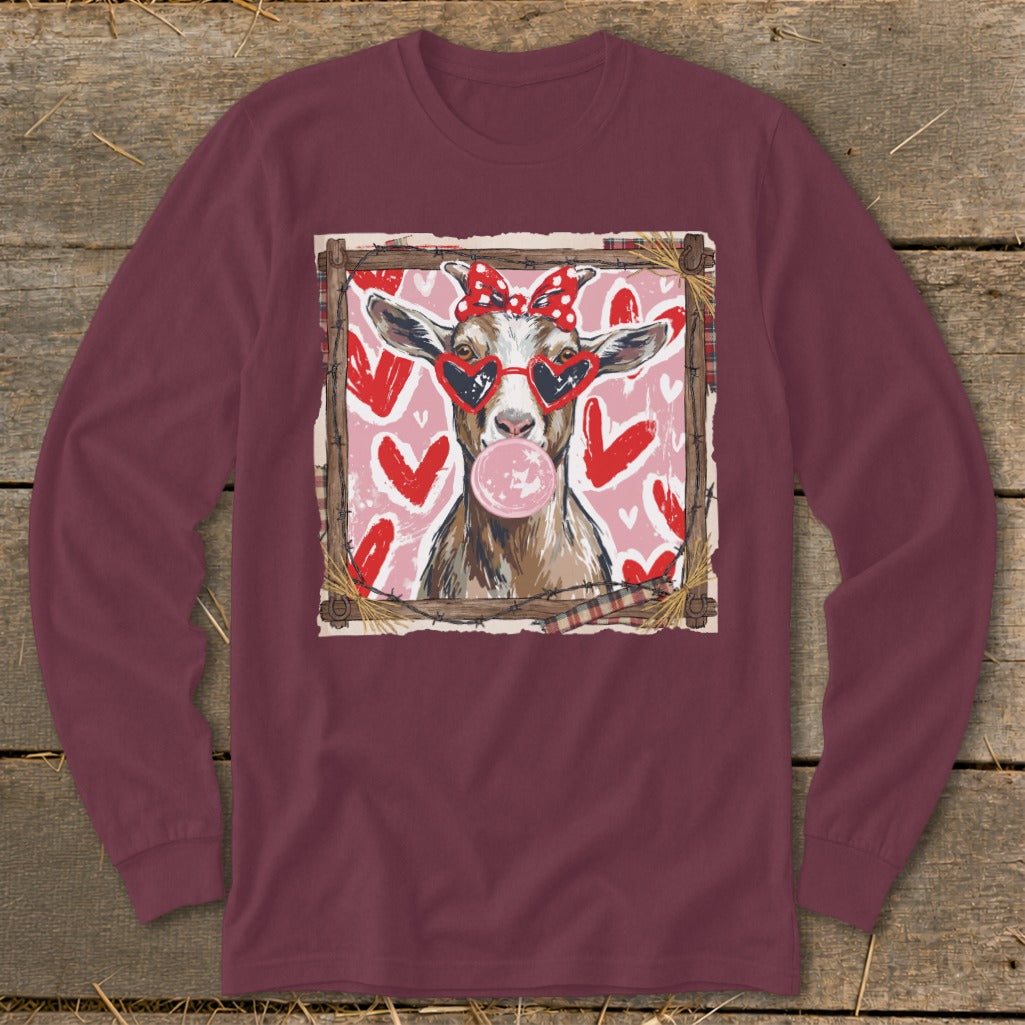 Goat wearing heart sunglasses and red bow blowing bubblegum, surrounded by hearts.