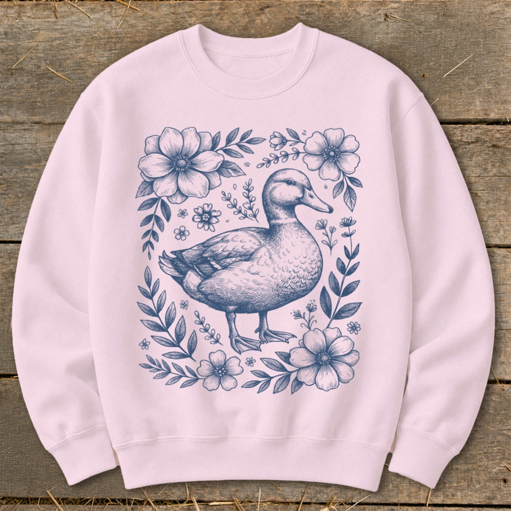 Pink sweatshirt with a navy blue duck illustration surrounded by flowers and leaves.
