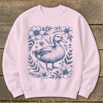 Pink sweatshirt with a navy blue duck illustration surrounded by flowers and leaves.