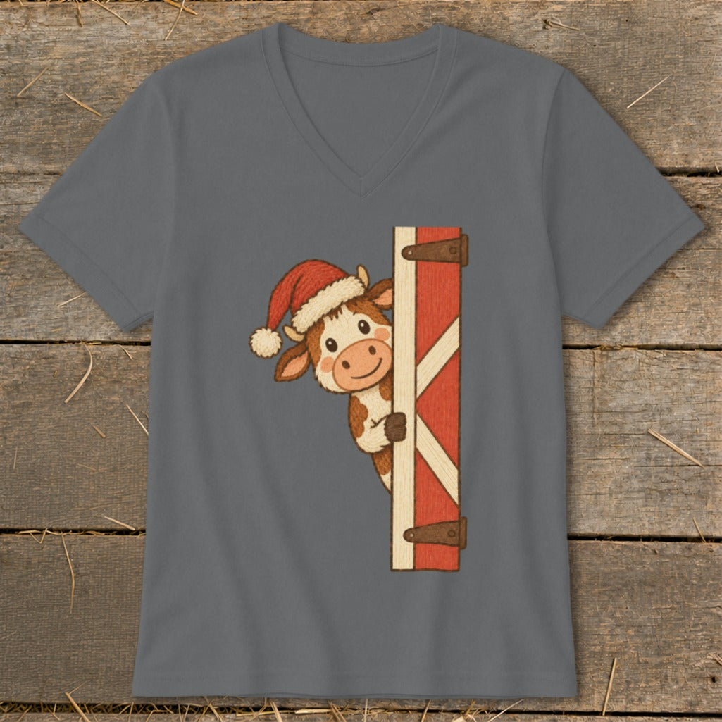 Cartoon cow wearing Santa hat peeking around a barn door.