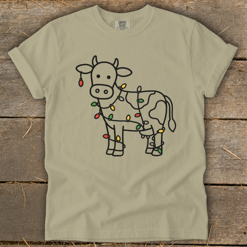 T-shirt with a black line drawing of a cow wrapped in colorful Christmas lights.