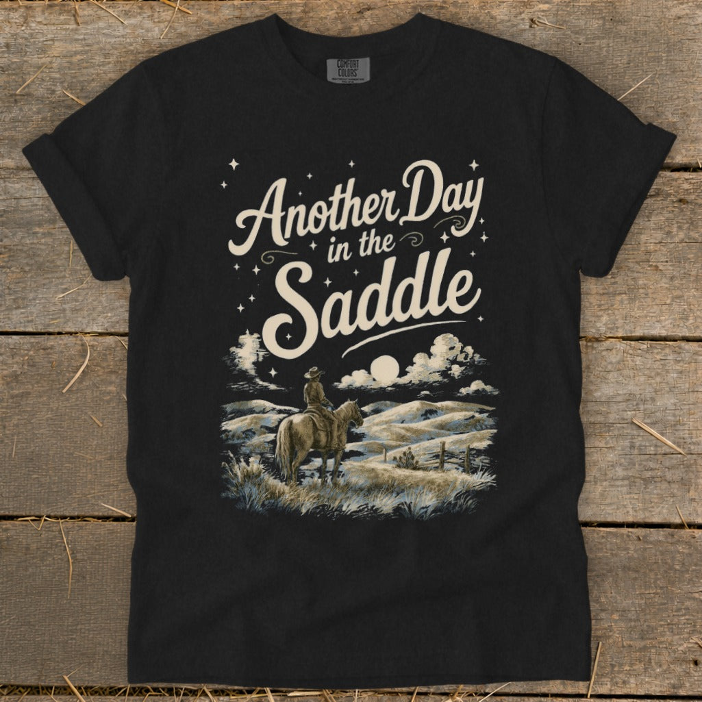 Black t-shirt with "Another Day in the Saddle" text above a ranch scene.