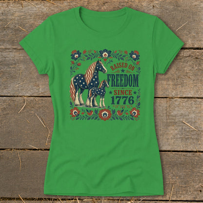 Green t-shirt with patriotic horses and "Raised on Freedom Since 1776" text.