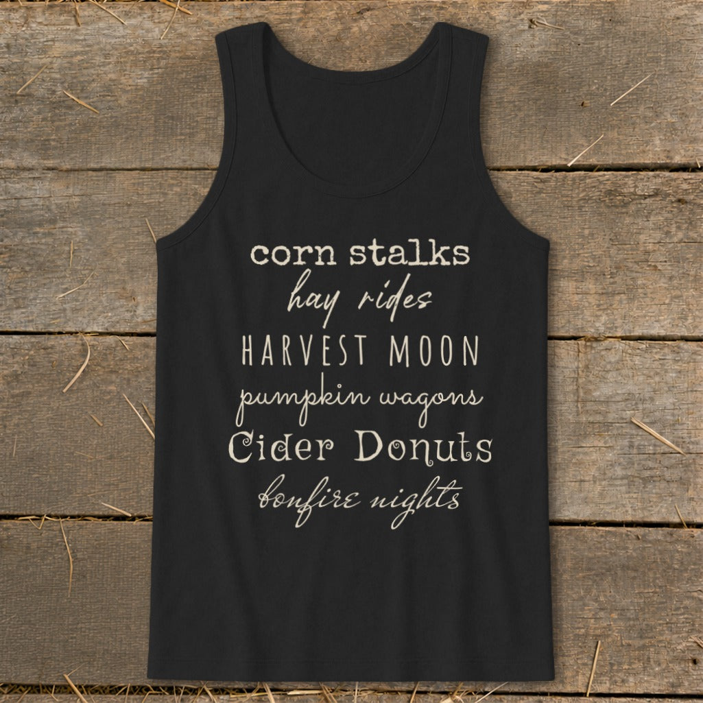 Black tank top with list of autumn phrases: corn stalks, hay rides, harvest moon, pumpkin wagons, cider donuts, bonfire nights.