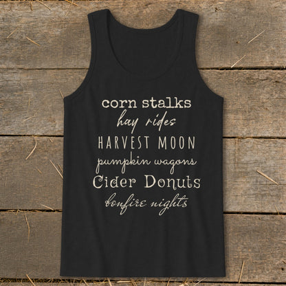 Black tank top with list of autumn phrases: corn stalks, hay rides, harvest moon, pumpkin wagons, cider donuts, bonfire nights.