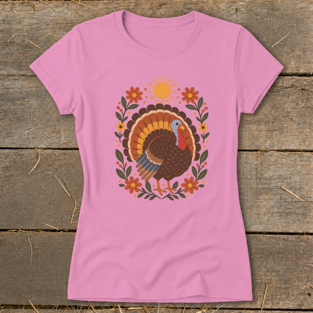 Pink t-shirt with a graphic of a turkey surrounded by flowers and a sun.
