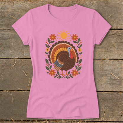 Pink t-shirt with a graphic of a turkey surrounded by flowers and a sun.