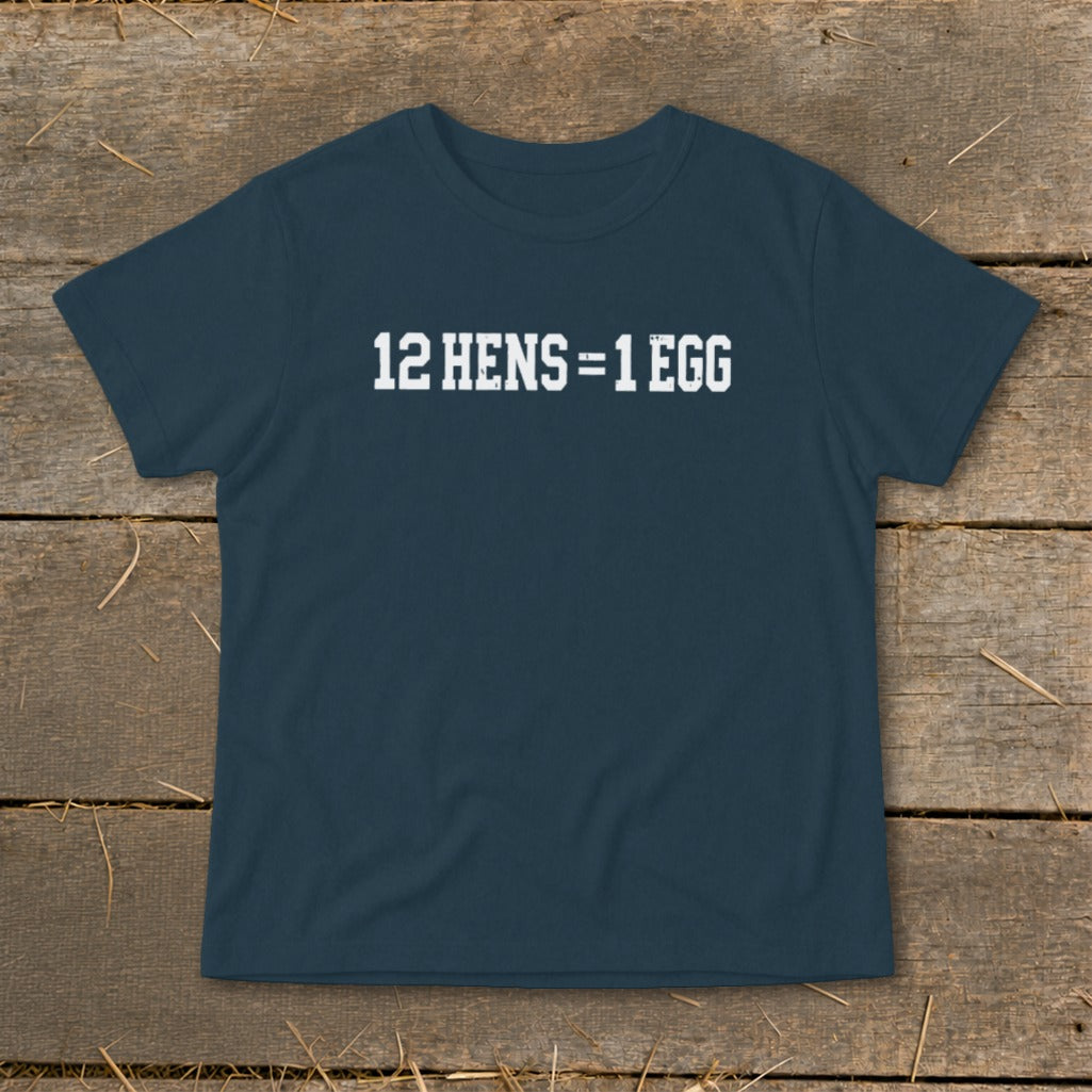 Dark blue short-sleeved t-shirt with white block text reading "12 HENS = 1 EGG" lying on wood.