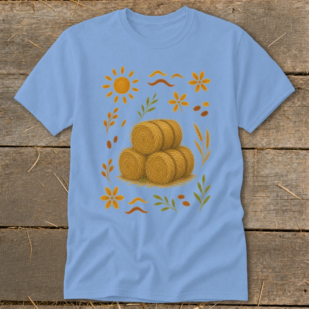 Light blue t-shirt with a pile of hay bales and autumn-themed illustrations.