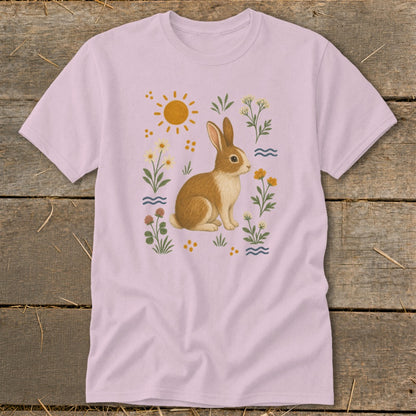 Pink t-shirt with a watercolor illustration of a brown rabbit surrounded by flowers and a sun.