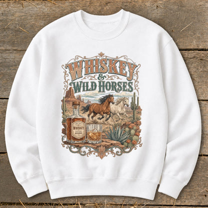 White sweatshirt with "Whiskey & Wild Horses" graphic featuring horses, whiskey bottle, and desert landscape.