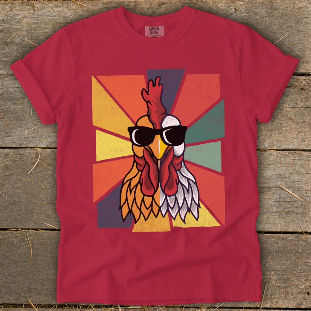 Red t-shirt with a vintage rooster graphic wearing sunglasses against a geometric sunburst background.
