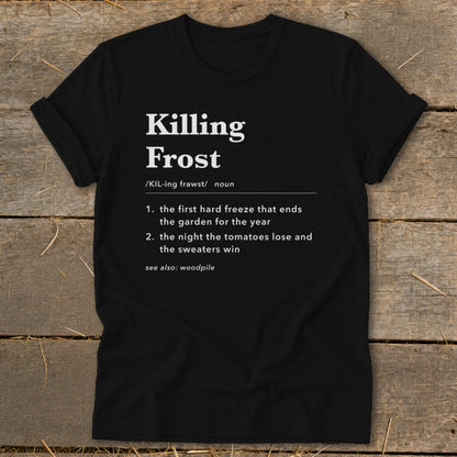 Black t-shirt featuring dictionary definition text for Killing Frost, laid flat on a rustic wooden surface.