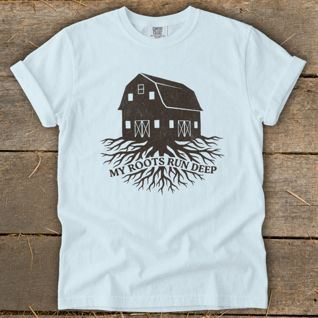 White t-shirt with a dark barn and roots graphic saying "MY ROOTS RUN DEEP."