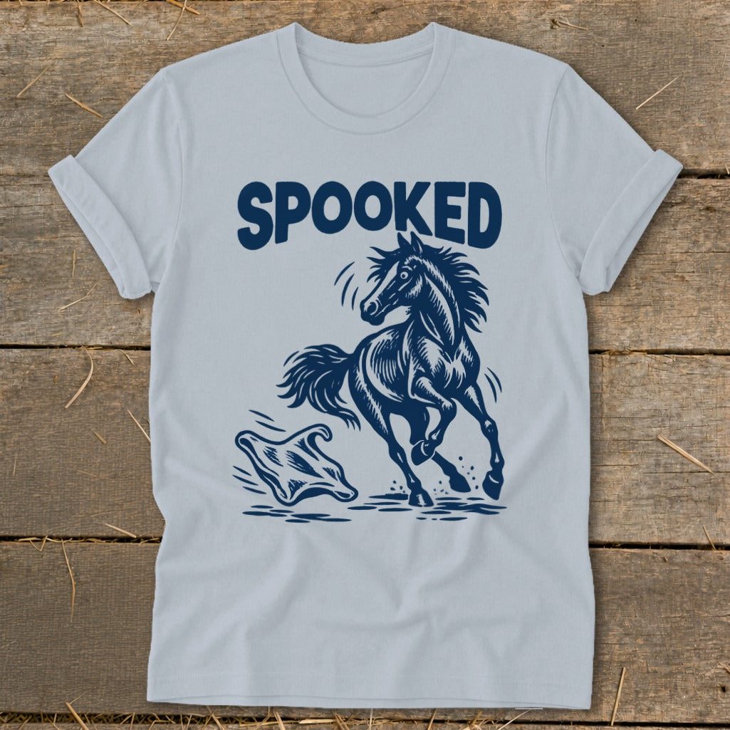 Light blue t-shirt with dark blue "SPOOKED" text above a startled horse and a ghost.