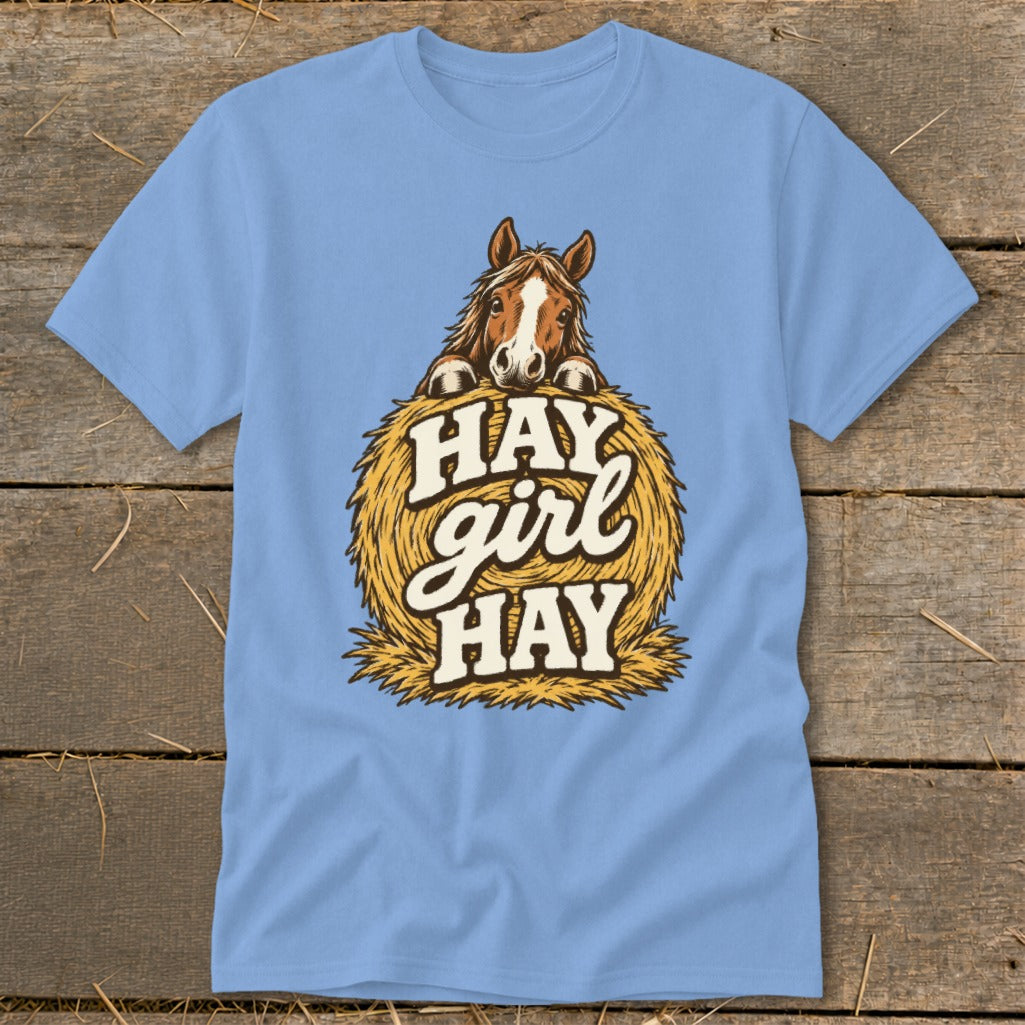 Light blue t-shirt with horse peeking over hay bale, "Hay girl hay" text.