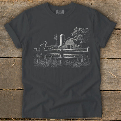 Cat sitting on a wooden fence with a barn and windmill in the background.