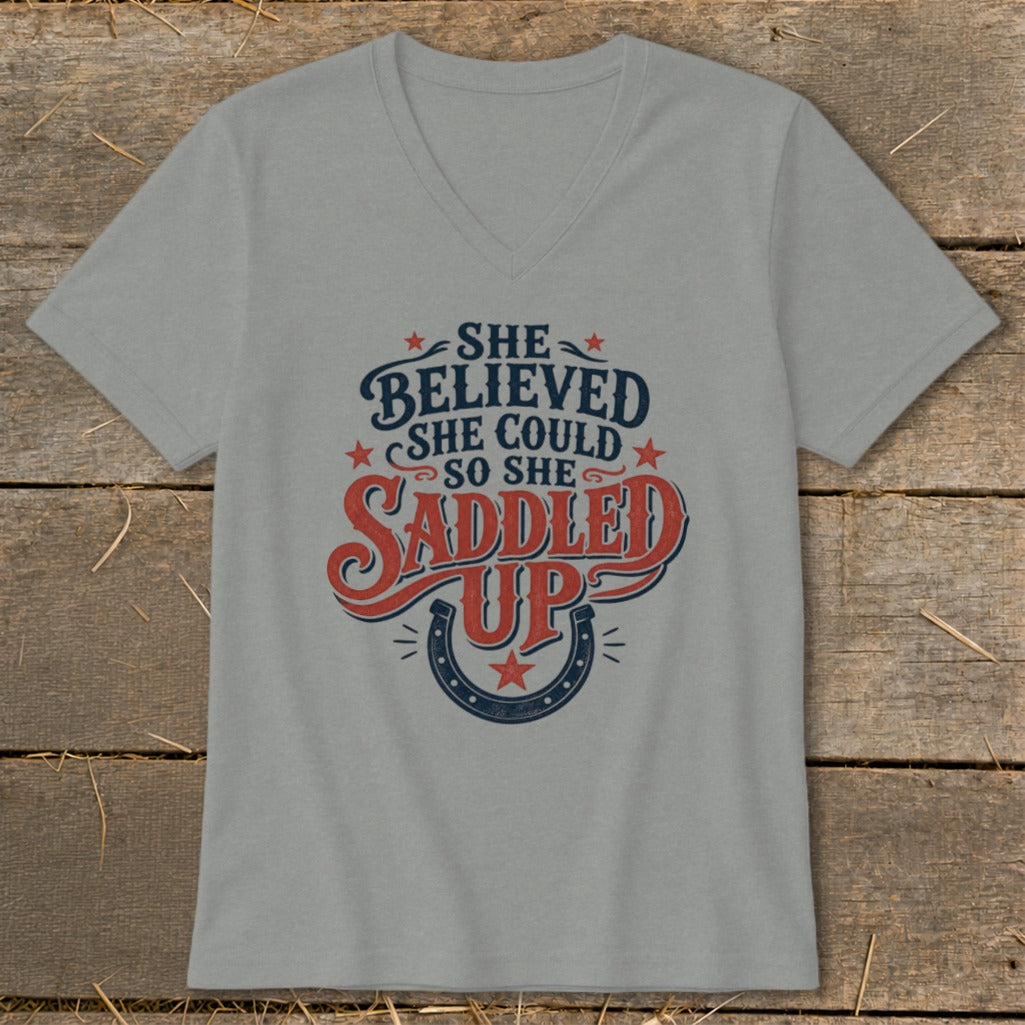 Grey v-neck t-shirt with "She believed she could so she saddled up" graphic.