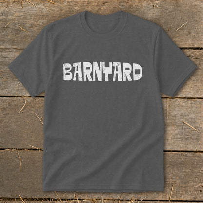 A dark gray crewneck t-shirt featuring the distressed white text "BARNYARD" centered on the chest, laid flat on a rustic wooden surface.