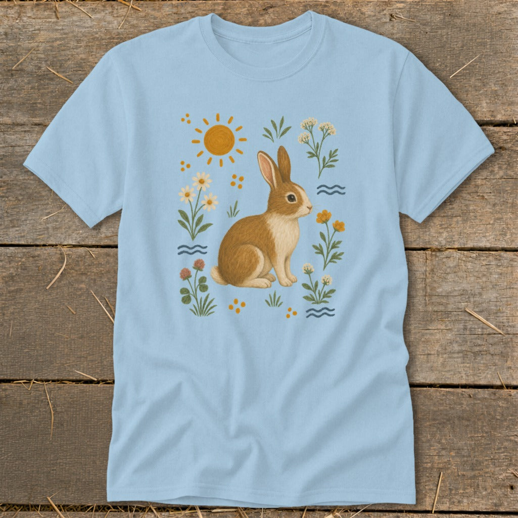 Light blue t-shirt with a graphic of a brown and white rabbit surrounded by flowers and sun.