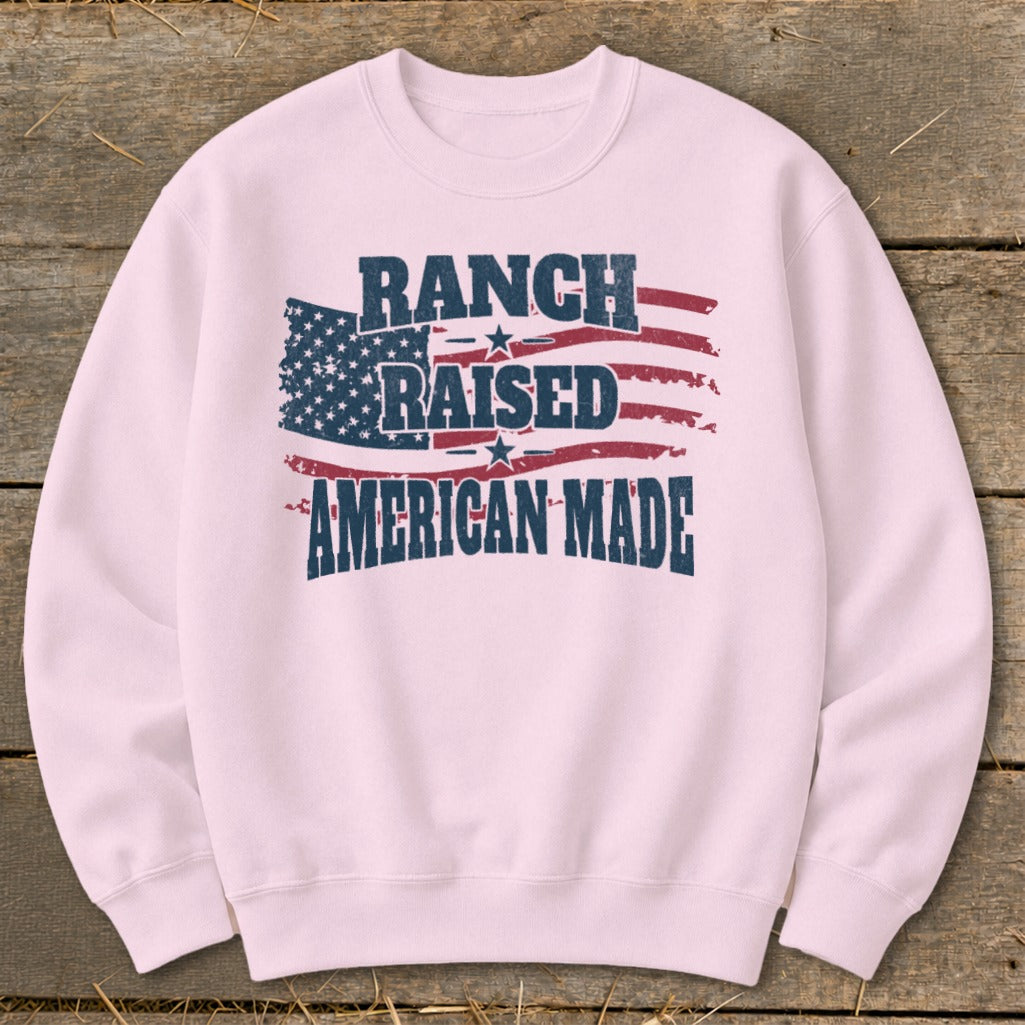 Pink crewneck sweatshirt with distressed American flag graphic and text "Ranch Raised American Made."