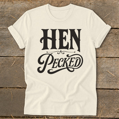 Cream t-shirt with black text reading "HEN PECKED" in a decorative font.