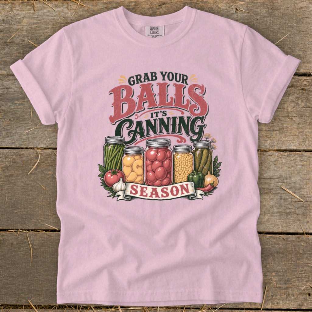 Pink t-shirt with "Grab Your Balls It's Canning Season" text and jars of pickled vegetables.