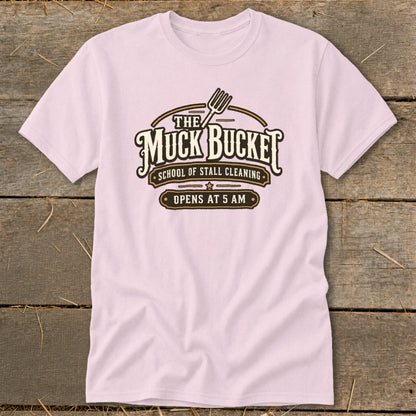 Pink t-shirt with "The Muck Bucket School of Stall Cleaning Opens at 5 AM" graphic.