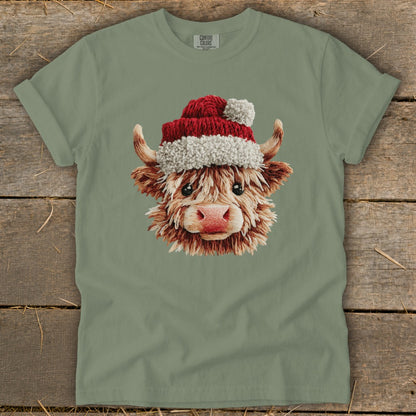Highland cow wearing a Santa hat on a green t-shirt.