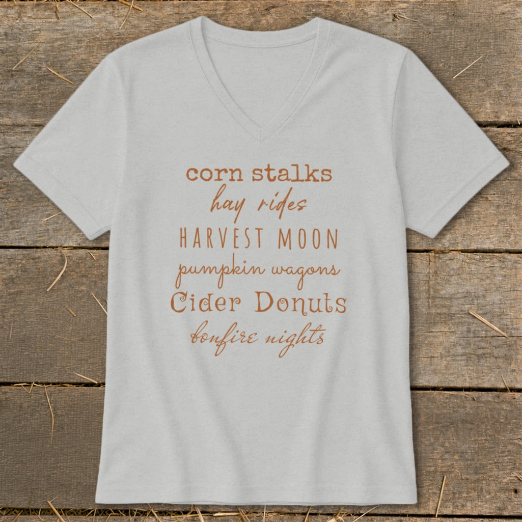 Light gray v-neck t-shirt with fall-themed text: corn stalks, hay rides, Harvest Moon, pumpkin wagons, cider donuts, bonfire nights.