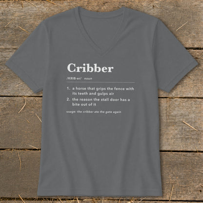 A dark gray V-neck t-shirt with white text defining the word cribber laid on a wooden surface.