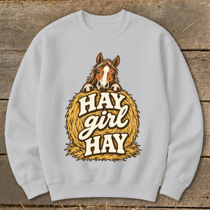 Light grey sweatshirt with a horse peeking over a hay bale with text "Hay Girl Hay".