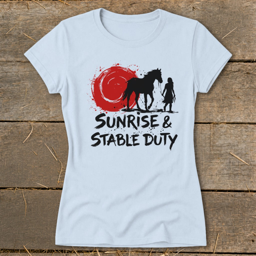 Light blue t-shirt with black silhouette of horse, rider, and red sun graphic. Text reads "Sunrise & Stable Duty".