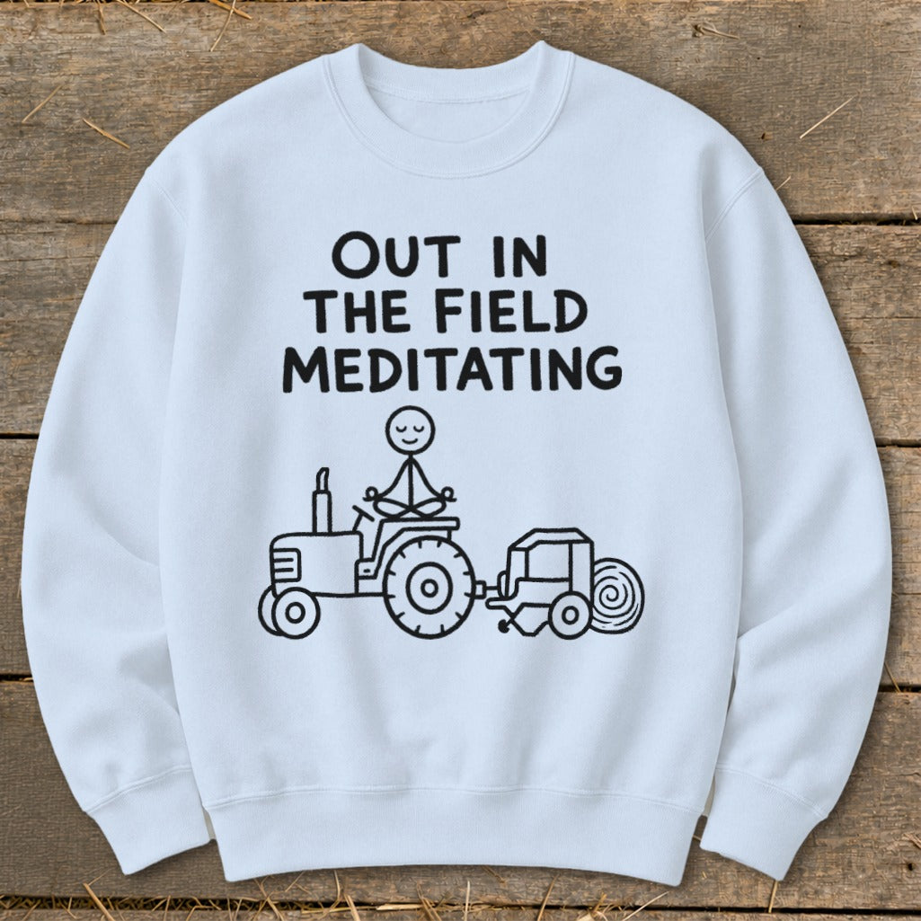 White sweatshirt with black text and illustration of a stick figure meditating on a tractor.