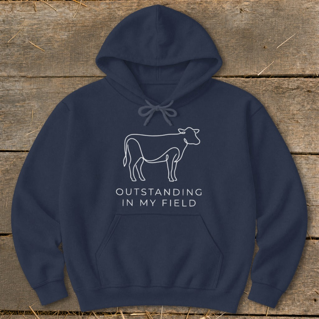 Navy hoodie with white cow outline and text "OUTSTANDING IN MY FIELD."