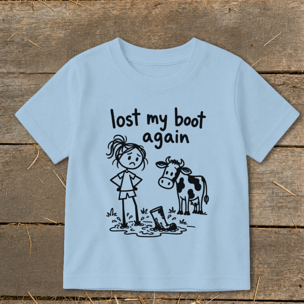 Light blue children's t-shirt printed with a cartoon stick figure, a cow, and the text lost my boot again.