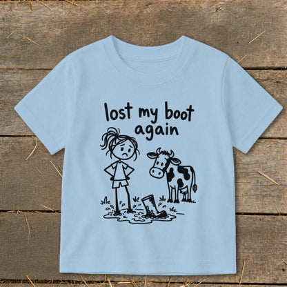 Light blue children's t-shirt printed with a cartoon stick figure, a cow, and the text lost my boot again.