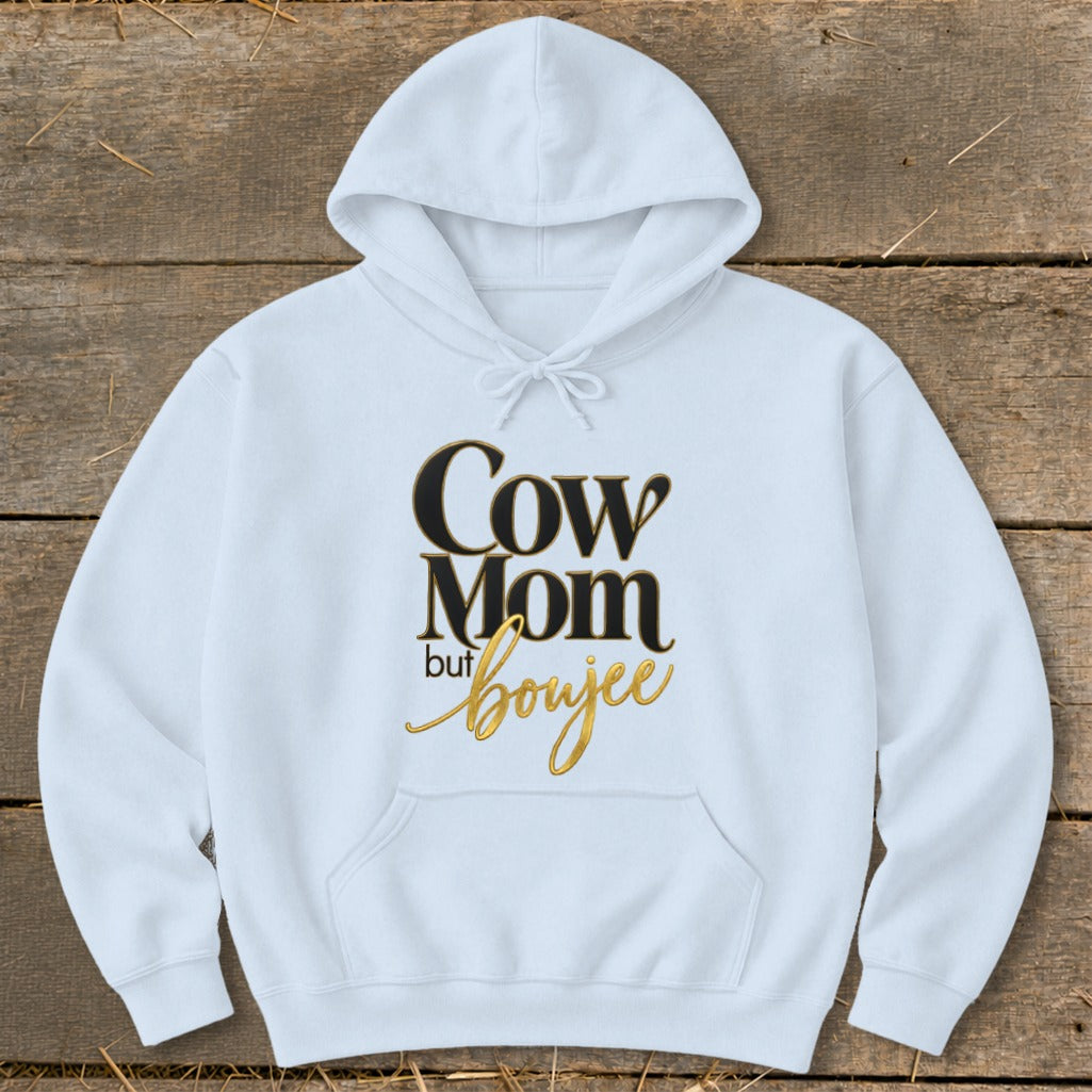 White hoodie with "Cow Mom but boujee" text in black and gold.