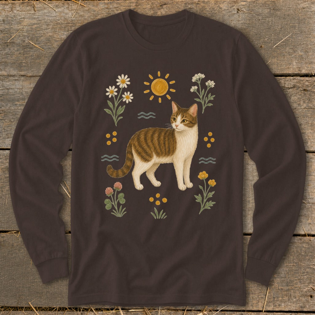 Brown long-sleeve shirt with a tabby cat illustration surrounded by flowers and sun.