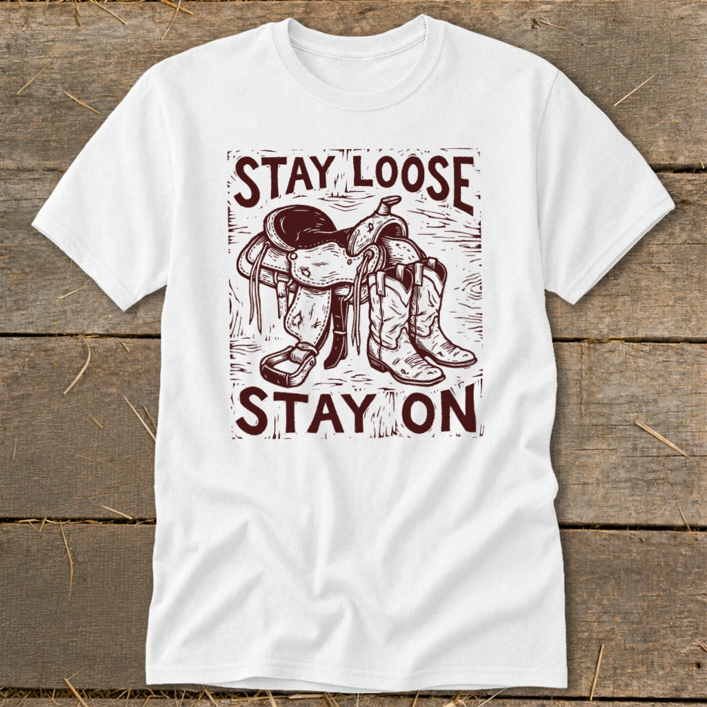 White t-shirt with cowboy boots, saddle, and text "STAY LOOSE STAY ON".