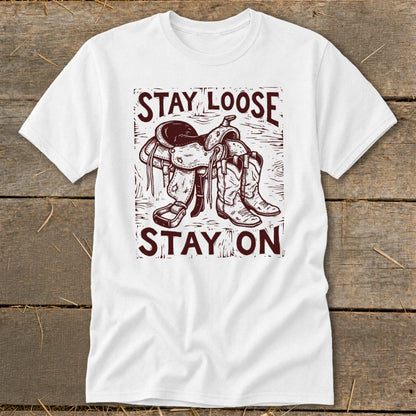 White t-shirt with cowboy boots, saddle, and text "STAY LOOSE STAY ON".