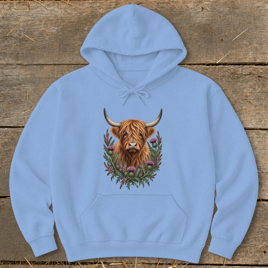 Light blue hoodie with a Highland cow portrait and thistle wreath graphic.