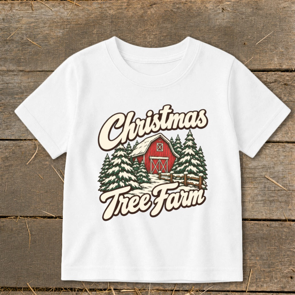 White t-shirt with "Christmas Tree Farm" graphic featuring a red barn and snow-covered pine trees.