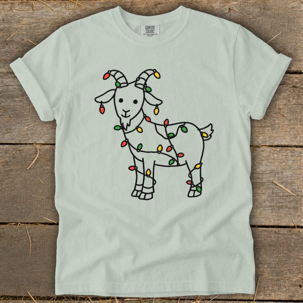 Light green t-shirt with a black line drawing of a goat wrapped in colorful Christmas lights.