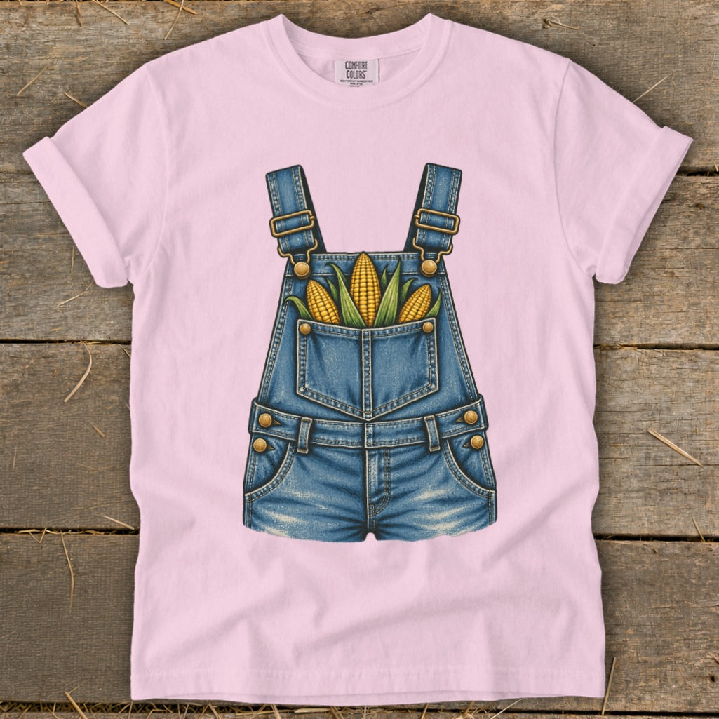 Pink t-shirt with a denim overalls graphic featuring corn in the pocket.