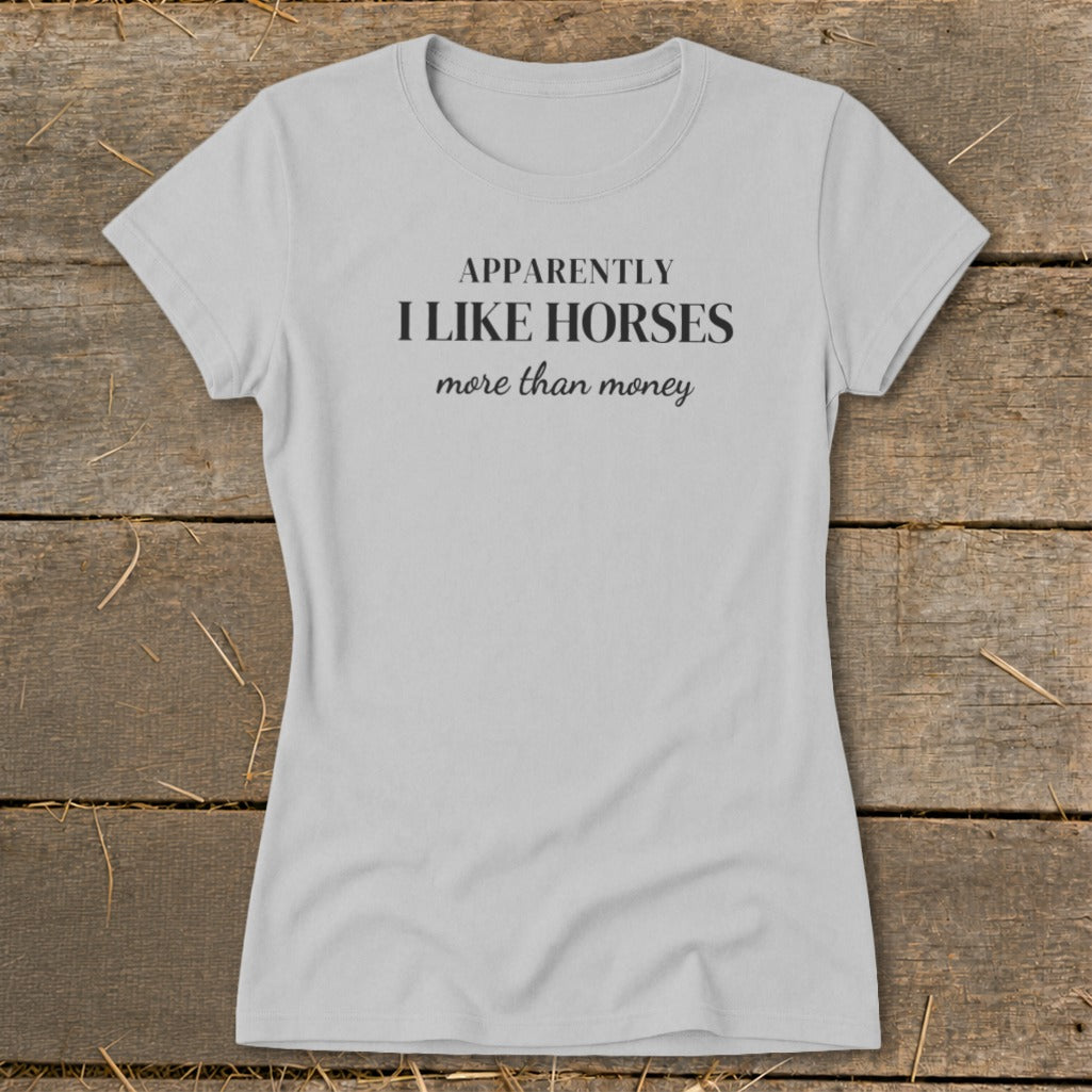 Light grey t-shirt with black text that reads "APPARENTLY I LIKE HORSES more than money".